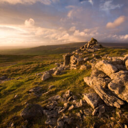 A walkerÕs cairn constructed high above Ingleton in North Yorkshire.  Made from scattered limestone rocks, the cairn catches the last of the sunshine on a stormy day.  Moorland grasses and weathered limestone outcrops meet the beautiful cloudscape above.