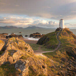 Twr Bach (Little Tower) is a lighthouse perched on the western tip of Llanddwyn Island, Anglesey.  The pale grey limestone in the fore contrasts with the dark grey basaIt on which the lighthouse is sited.  Ynys Llanddwyn a tidal island connected to Anglesey by a stretch of sand and is part of the Newborough Warren National Nature Reserve. The peaks of the Lleyn Peninsula can be seen across Caernarfon Bay.
